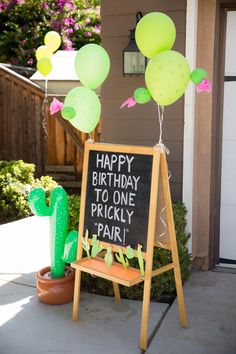 a sign that says happy birthday to one pricky pair with balloons in the air