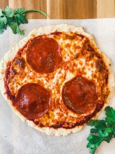 a pepperoni pizza sitting on top of a piece of paper next to parsley