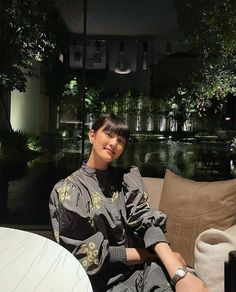 a woman sitting on top of a couch next to a table