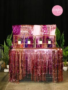 a table topped with lots of pink and purple tinsel next to potted plants