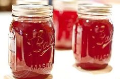 four jars filled with red liquid sitting on top of a table