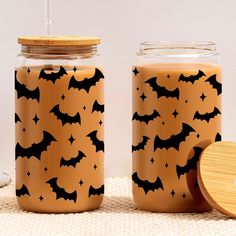 two jars with bats painted on them next to a wooden container filled with something else