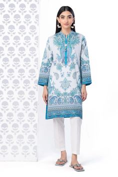 a KHAADI 1 piece SHIRT woman standing in front of a white wall White Cotton Tops For Eid, Long Sleeve Blue Tops For Eid, Casual Long Sleeve Blouse With Printed Motifs, Casual White Top For Eid, White Cotton Tops With Printed Motifs, White Cotton Top With Printed Motifs, Casual Cotton Tops For Eid, Long Sleeve Cotton Tops For Eid, White Tops With Printed Motifs