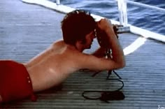 a shirtless man sitting on the deck of a boat