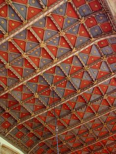 an ornate ceiling with red, blue and gold tiles on the ceiling is seen in this image