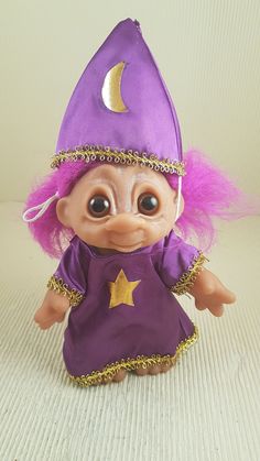 a purple and gold troll doll wearing a purple dress with stars on it's head