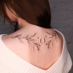 the back of a woman's neck with leaves and stars on it