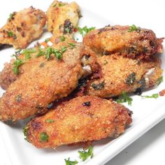 some fried food on a white plate with parsley sprinkled around the edges