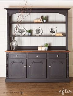 an old china cabinet is painted black and has some plants on top of the hutch