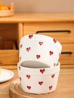 two bowls with hearts painted on them sitting on a table