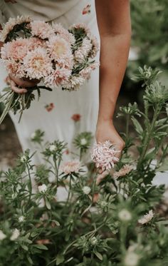 a woman in a white dress holding pink flowers