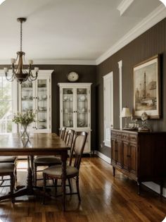 a dinning room table and chairs in front of a china cabinet with glass doors