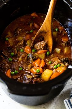 a wooden spoon in a pot filled with stew