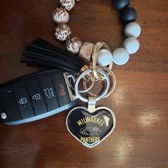 a black and white beaded necklace with a heart shaped keychain attached to it