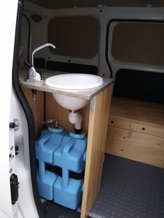 the inside of a van with two blue containers and a sink