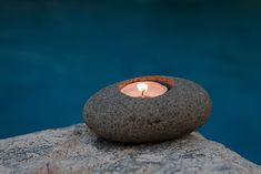 a lit candle sitting on top of a rock