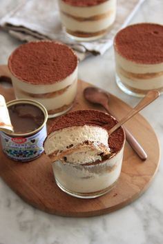 three desserts are sitting on a wooden platter with spoons next to them