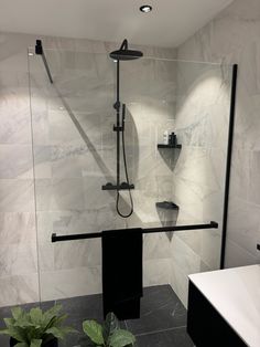 a bathroom with black and white tile walls, shower head, and shelves on the wall