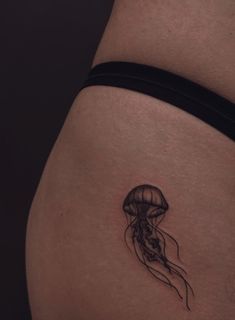 a woman's thigh with a small tattoo of a jellyfish