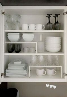 white dishes and cups are stacked on shelves in the kitchen, with hearts drawn on them