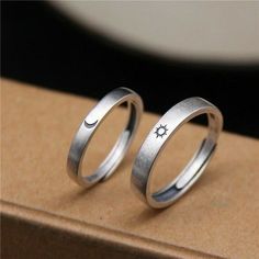 two silver rings sitting on top of a cardboard box