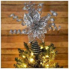 a silver snowflake ornament on top of a christmas tree with lights