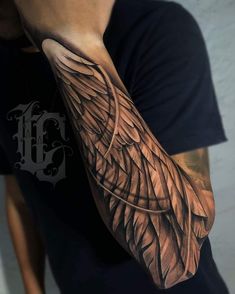 a man's arm with an angel wing tattoo on it