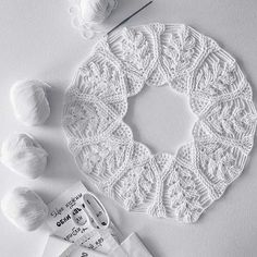 white crochet doily, yarn and needles laid out on a table