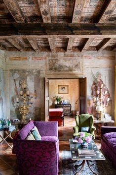 a living room filled with purple couches next to a painting on the wall and ceiling