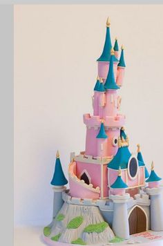 a pink and blue castle cake sitting on top of a table