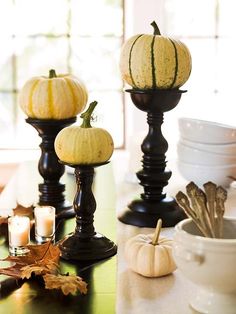 two pumpkins sitting on top of black candlesticks