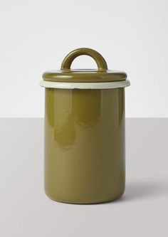 a green canister with a handle on the top, sitting on a white surface