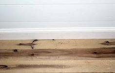 wood flooring with white paint on the wall and bottom part of the door frame