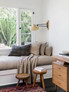 a living room with a couch, table and chair next to a window that has cactus plants on it