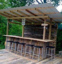 an outdoor bar made out of pallets and wooden planks with stools under it