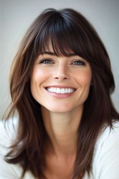 Wispy Layers with Bangs Hairstyle on a smiling woman with brown hair. Angled Bob, Chic Hairstyles