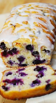 a loaf of blueberry bread with white glaze on top is cut in half