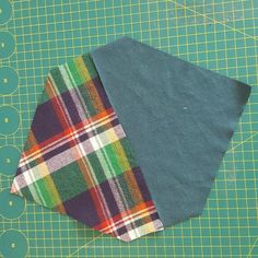 two pieces of fabric sitting on top of a green cutting mat next to each other