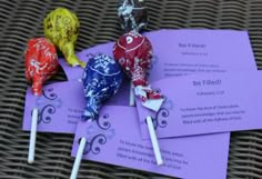 three candy lollipops sitting on top of purple paper