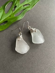 Sea glass and silver plated earrings. These earrings are on silver wires, with silver wire wrap design, and each earring has one piece of mount shaped sea glass. These are clear beach glass. They are (about 1.4 inches long), they are a tick.  All the sea glass I use, I find on California beaches. Generally, I use the most well-rounded pieces because they have a softer, more elegant look.  Purchases come in a gift box or cloth bag. You can choose which one you like. Clear Beaches, California Beaches, Cloth Bag, Dangly Earrings, Beach Glass, Wire Wrap, Silver Wire, Cloth Bags, Sea Glass