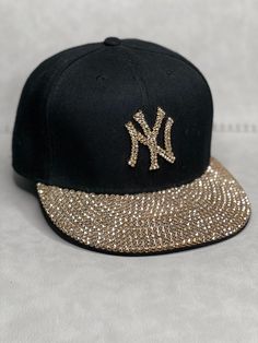 This is a Black New Era 59 Fifty NY Yankees fitted hat that is hand embellished with genuine rose gold Swarovski crystals on the front logo and bill of cap. This hat features over 500+ Swarovski crystals. - 100% Cotton - Several sizes offered, this is a fitted hat - Raised Embroidered Logo - 500+ rose gold Swarovski crystals individually placed by hand - Ready to ship in 1 week from San Diego, CA Luxury Fitted Hat With Pinched Crown, Cheap Black Fitted Hat With Letter Print, 59fifty Hats Custom New Era Cap, Ny Yankees Hat Outfit, Y2k Hats, Ny Hats, Ny Yankees Hat, Yankees Fitted Hat, Bling Hat