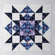 a blue and pink quilted square with flowers on the center, in front of a white background