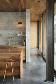 a kitchen with an island counter and stools in front of the sink, next to a large window