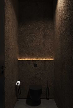 a black toilet in a dark bathroom with lights on the wall and floor below it