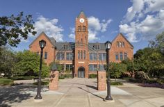 a large brick building with a clock tower on the top and two black street lamps in front