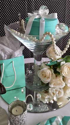 a table topped with a glass vase filled with white flowers and pearls on top of it