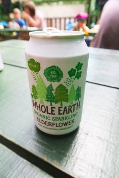 a can of whole earth organic sparkling elderflower on a picnic table with people in the background