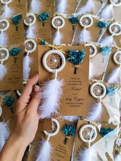 a person is holding up some cards with feathers and beads on them in front of other cards