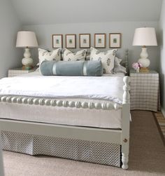 a white bed sitting under a chandelier in a bedroom next to two lamps