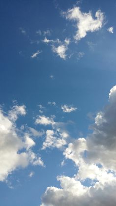 the airplane is flying high in the blue sky with white clouds above it and below